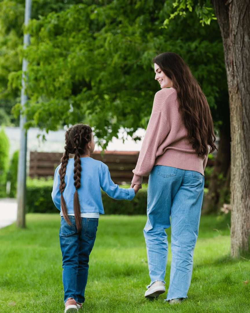 Mother and daughter holding hands walking in a park