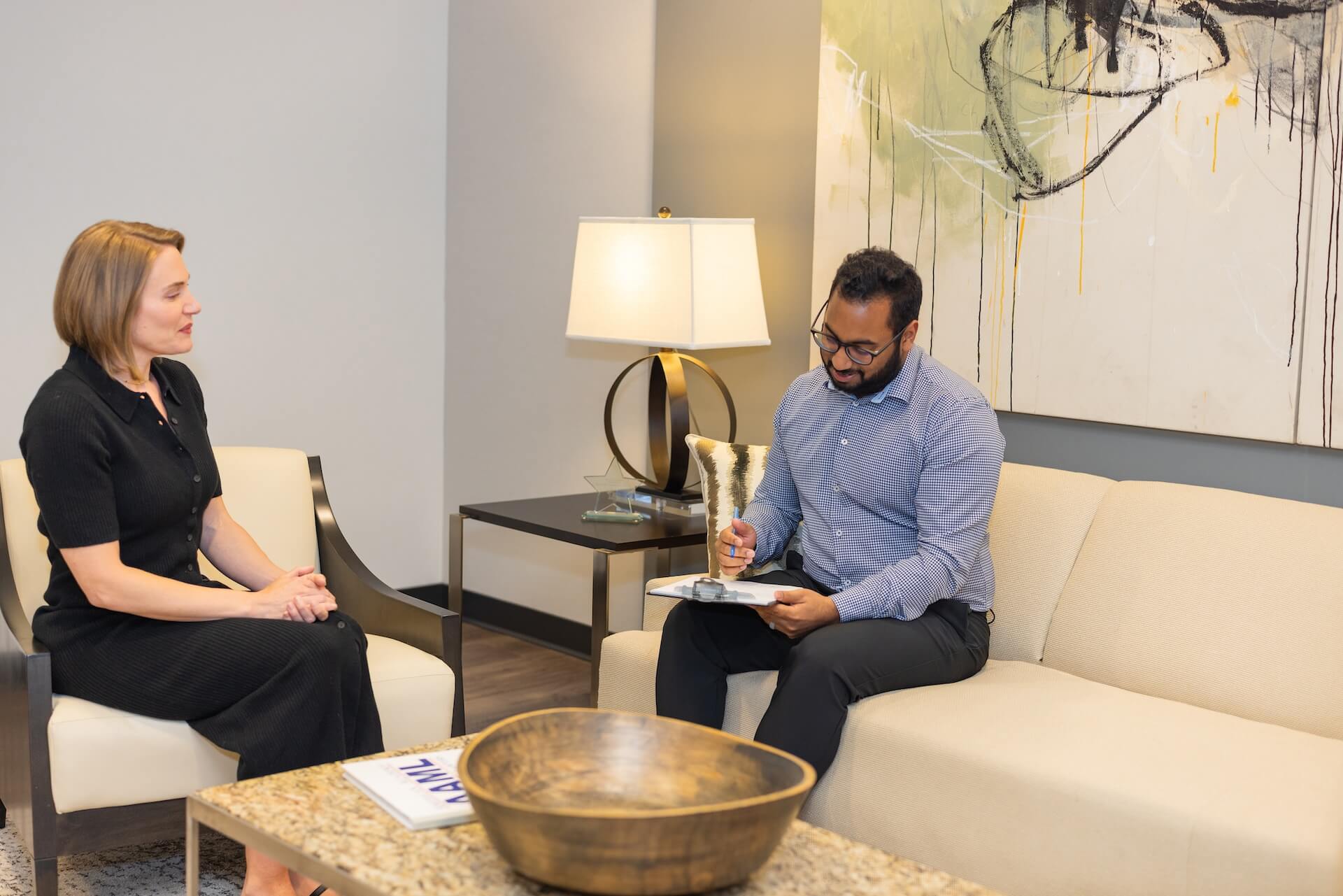 Attorney taking notes while consulting with a client in the office lounge