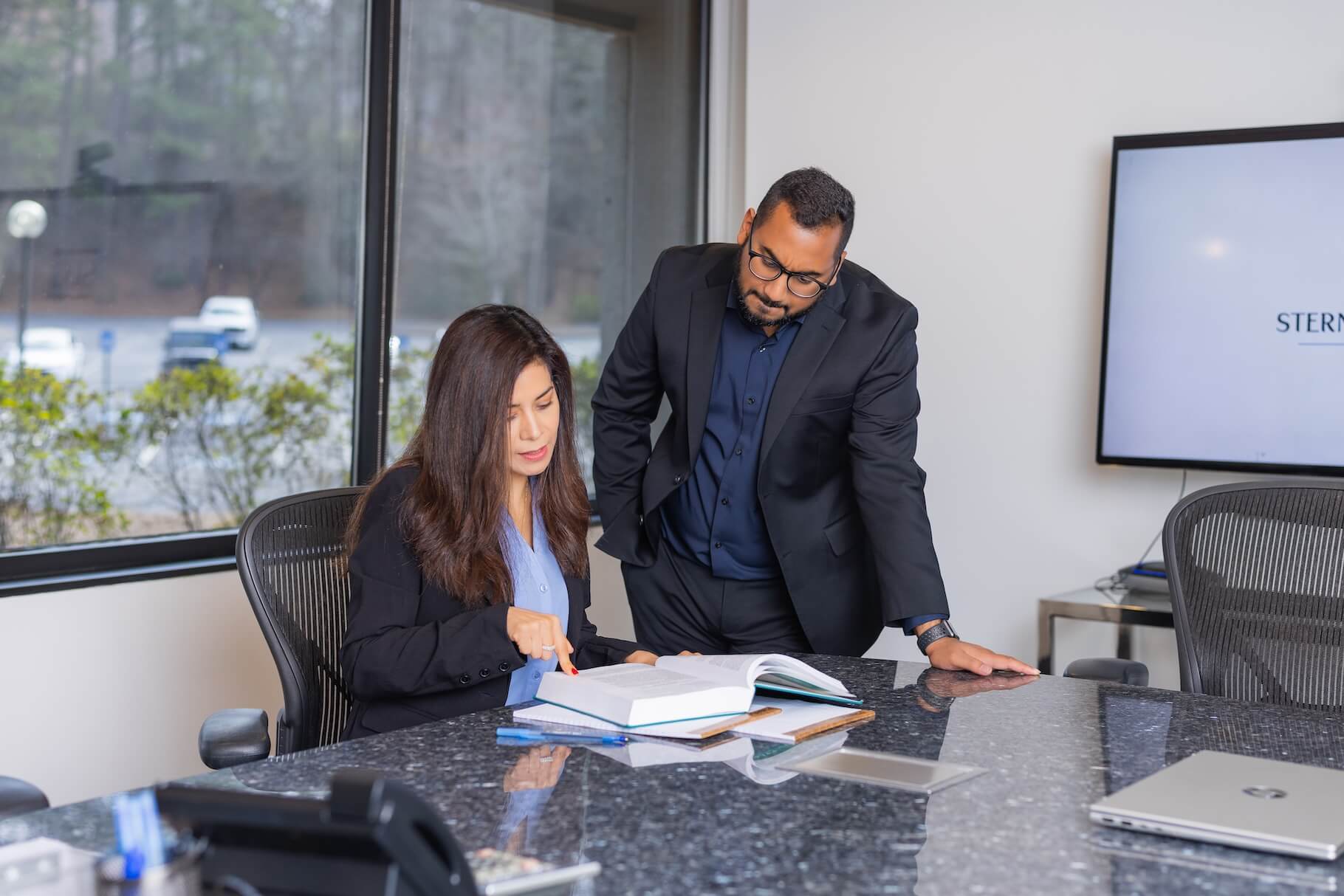 Two attorneys reviewing a case file together in the conference room