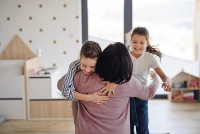 Two children joyfully hugging their mother at home
