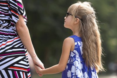 Parent and child holding hands outdoors, representing enforcement of court orders
