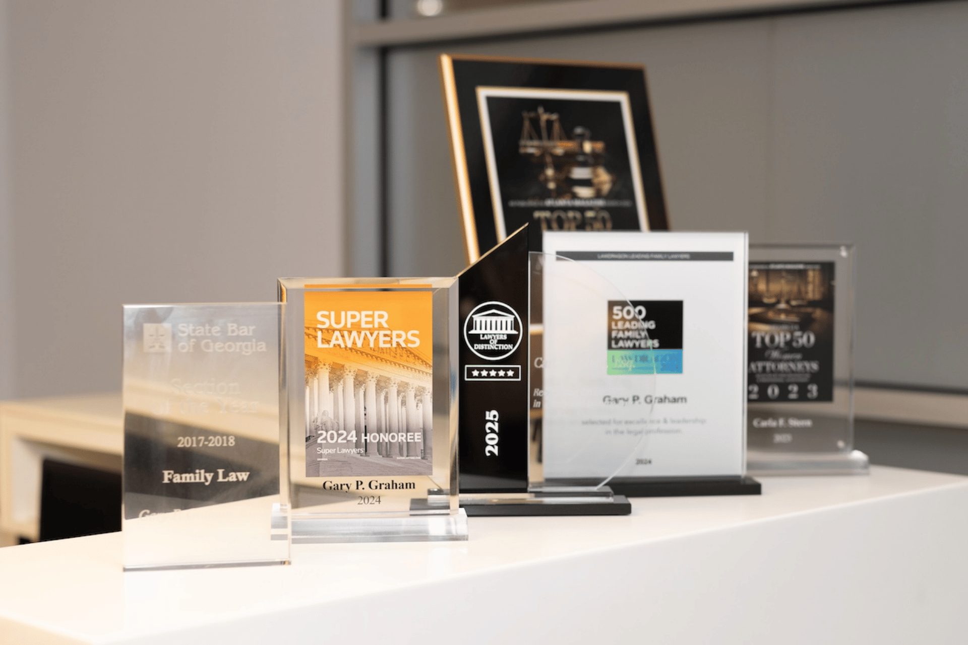 Award plaques and trophies displayed on a shelf, including Super Lawyers and Best Family Lawyers recognitions