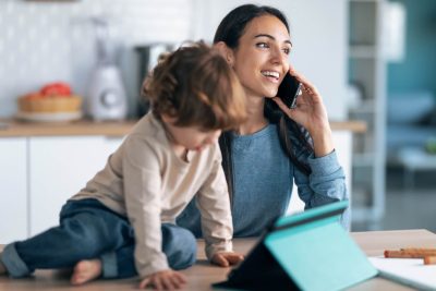 Woman smiling while talking on the phone with her child nearby